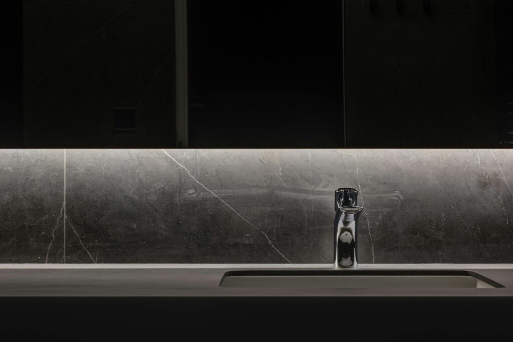 Sleek minimalist bathroom with a modern illuminated faucet and washbasin.